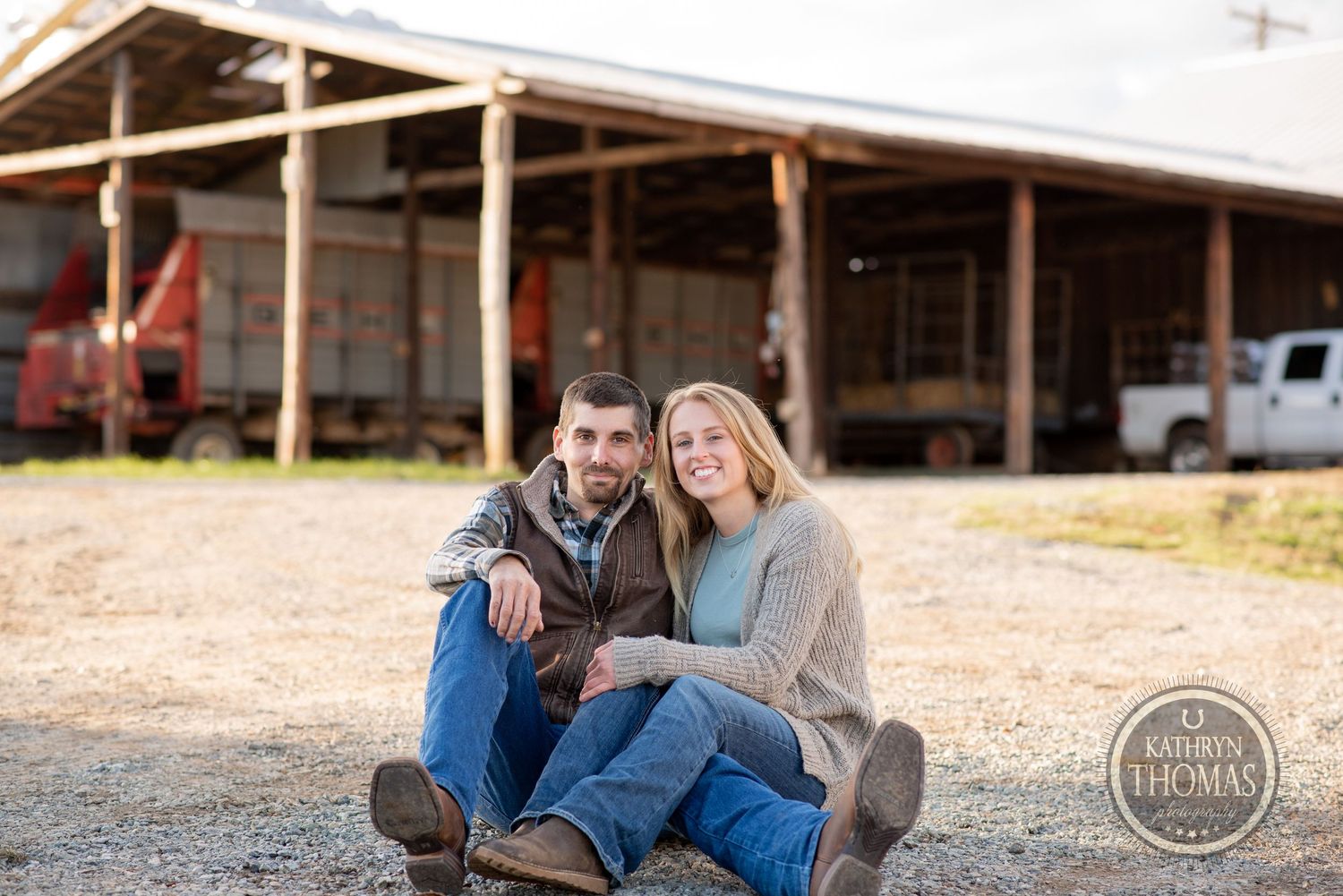 Couple sitting casually together outside rustic farm building during sunset.
