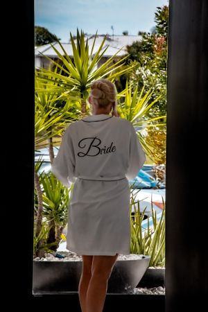 White robe with 'Bride' text seen from behind overlooking tropical garden setting.