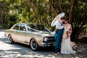 Classic vintage car parked in a shaded area during a wedding photoshoot.