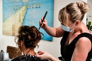 Behind the scenes preparation with hairstyling taking place in front of blue wall art.
