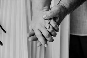 Close-up of couple holding hands showing wedding rings.