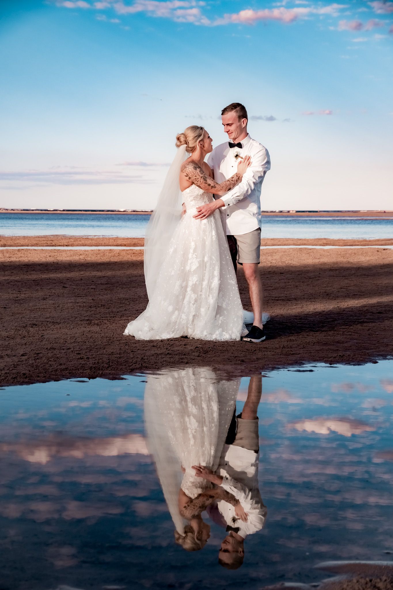 Beach wedding photos with reflections in wet sand during sunset.