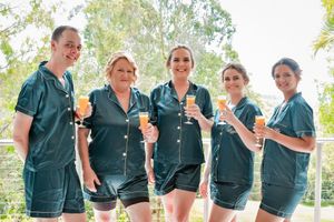 Group in matching green pajama sets holding champagne glasses outdoors.