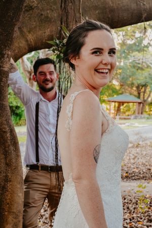 Joyful moment captured between newlyweds under a tree during their outdoor wedding photoshoot.