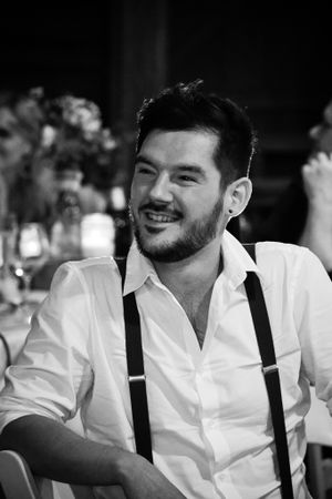 Black and white portrait of a person in suspenders and white shirt at a formal event.