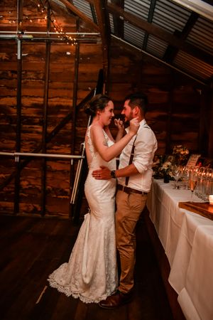 A couple sharing an intimate dance moment in a rustic barn wedding venue with string lights.