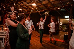 Wedding guests dancing and celebrating in a rustic barn venue with string lights.