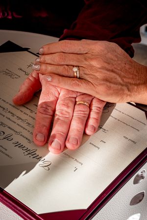 Hands with wedding rings signing a document in a formal book.