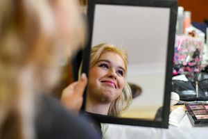 Reflection in mirror showing preparation with makeup and styling products.