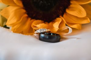 Wedding rings displayed with a bright sunflower petal in the background.