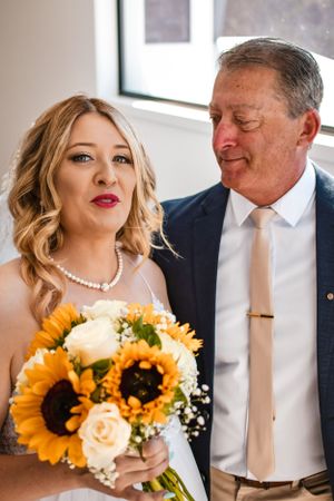 Wedding moment with sunflower bouquet featuring bright yellow blooms and white roses.