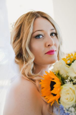 Elegant bridal portrait with sunflower and rose bouquet in natural light.