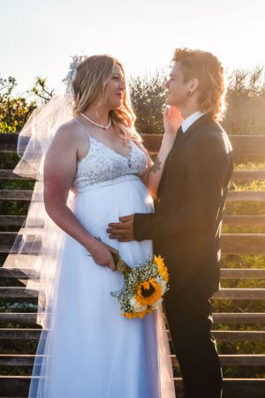 Sunset wedding portrait with couple and sunflower bouquet on outdoor steps.