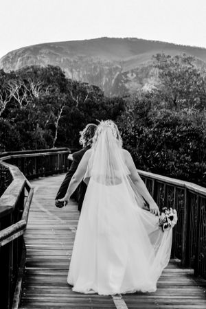 A wedding dress silhouette on a wooden mountain overlook with dramatic mountain peaks in the background.