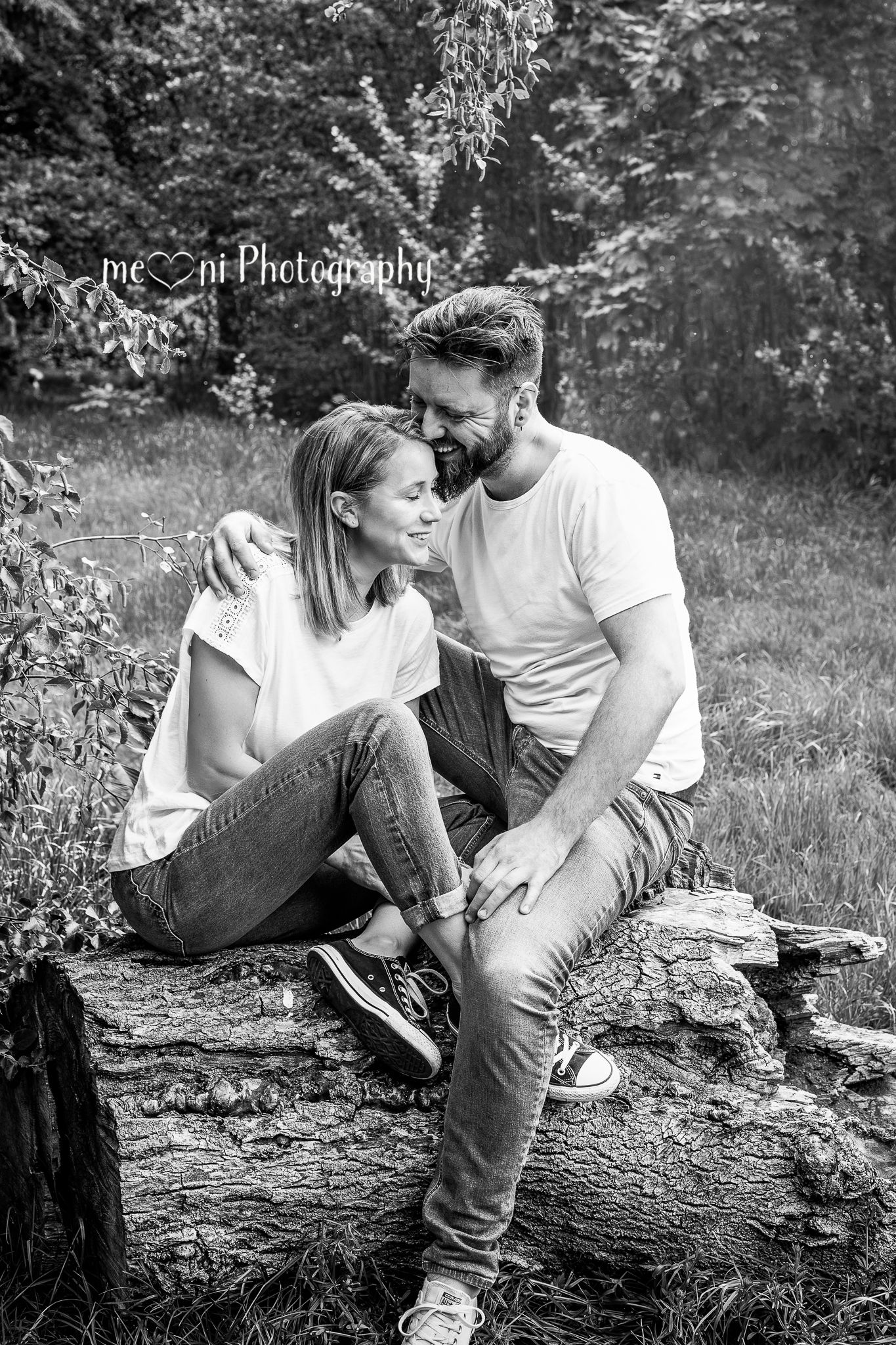 Black and white couples photoshoot on fallen log in natural woodland setting.