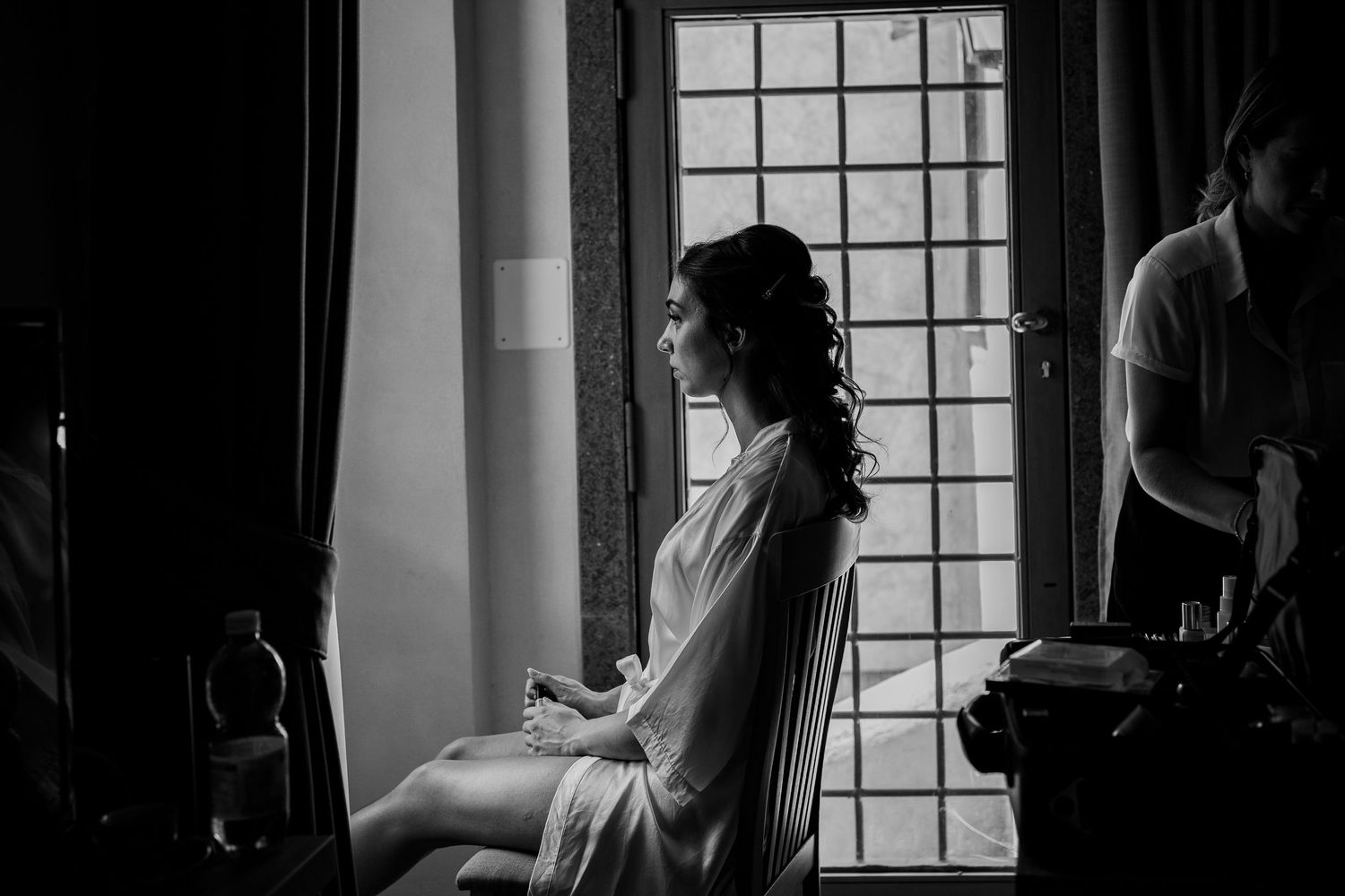 Light streams through a window as a figure sits in silhouette during morning preparations.