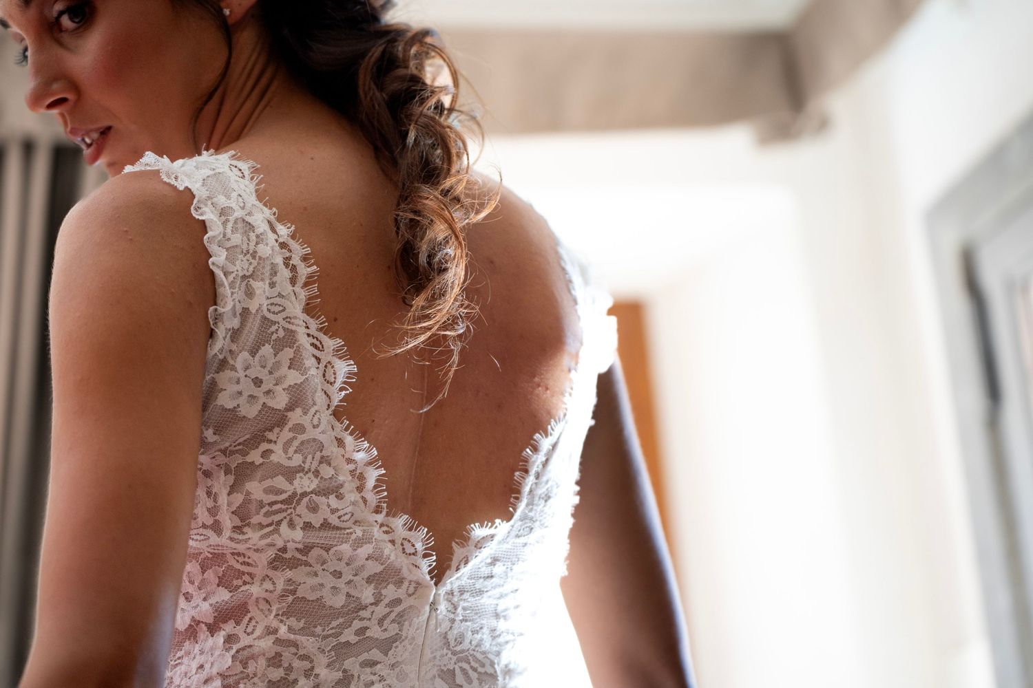 Detailed back of a white lace wedding dress with intricate scalloped edges.