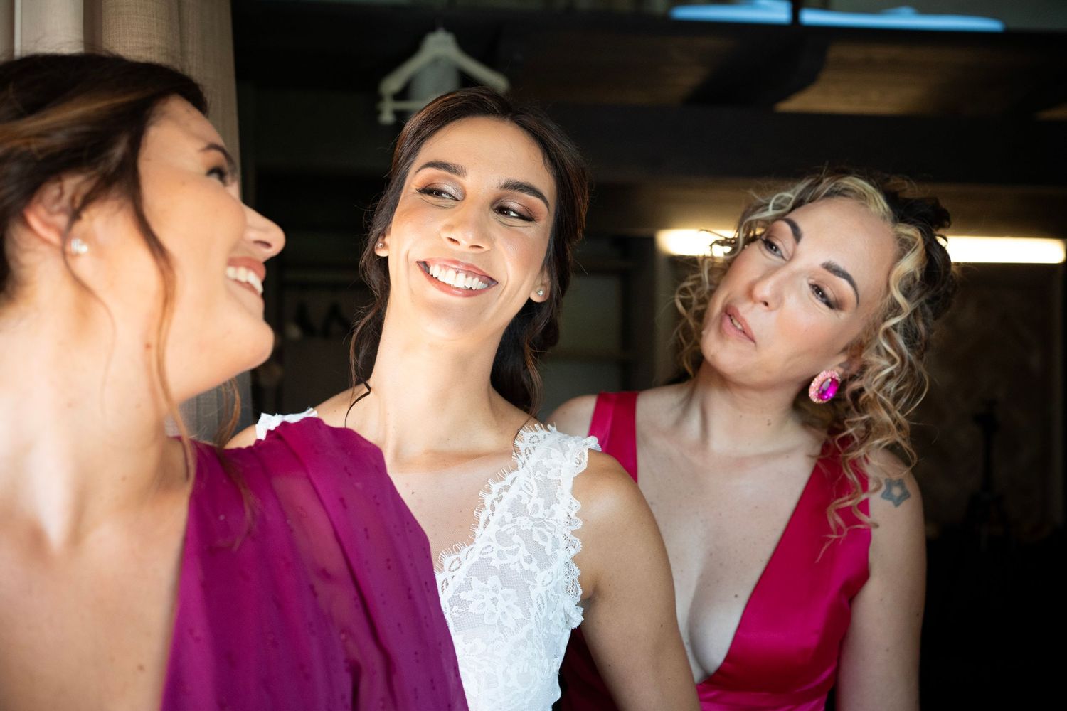 Wedding party members in white and magenta dresses share a joyful moment.