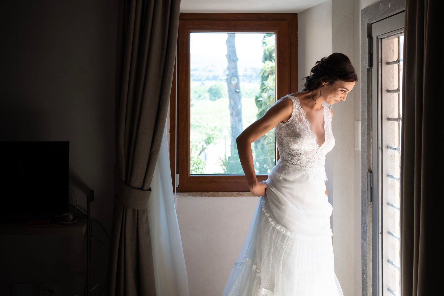 Elegant white wedding dress photographed near a window in natural light.