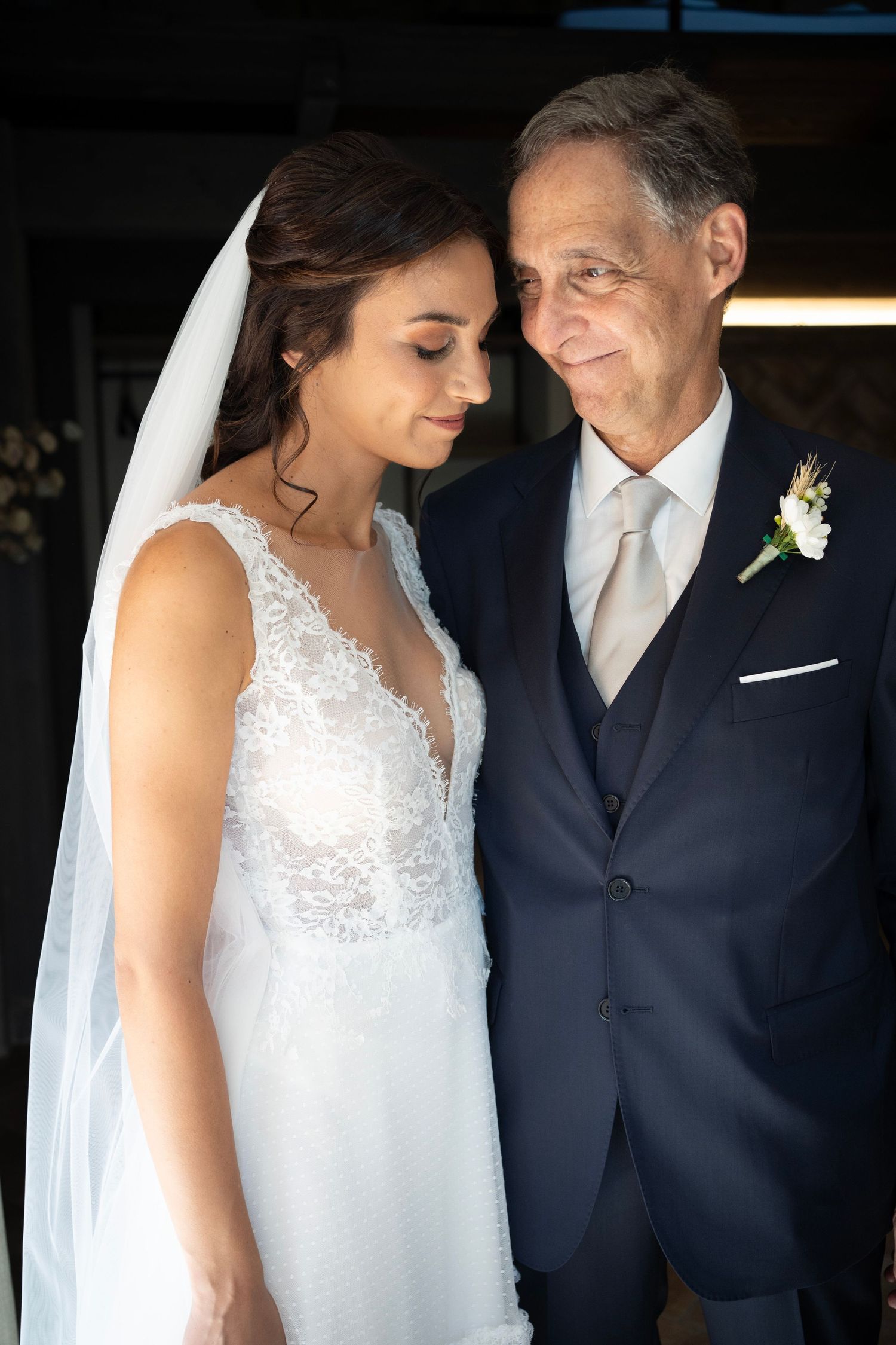 A tender moment captured during a wedding ceremony with elegant formal attire and traditional white gown.