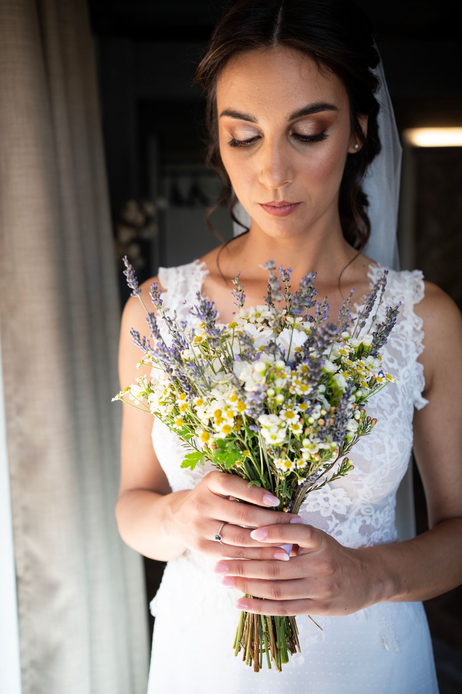 Close-up of bridal bouquet with wildflowers and lace dress details.