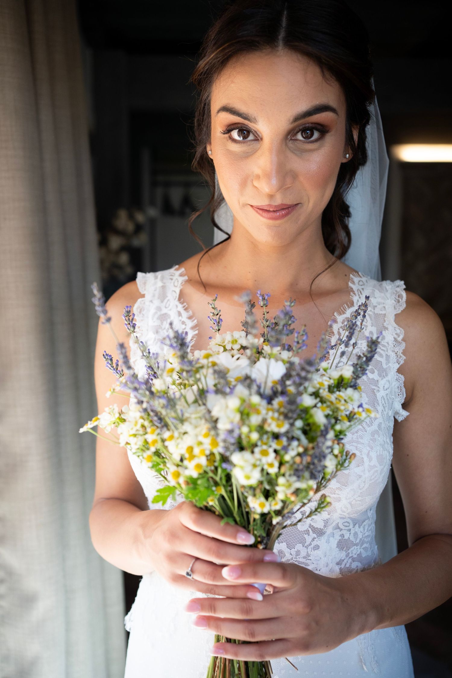 Elegant bridal portrait with delicate wildflower bouquet featuring lavender and daisies.