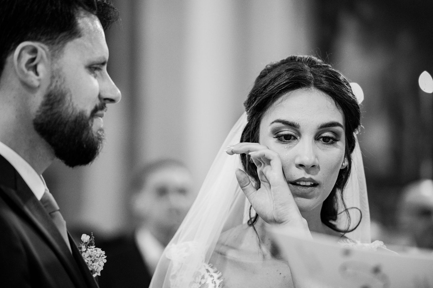 Intimate black and white portrait from wedding ceremony with bride in traditional veil.