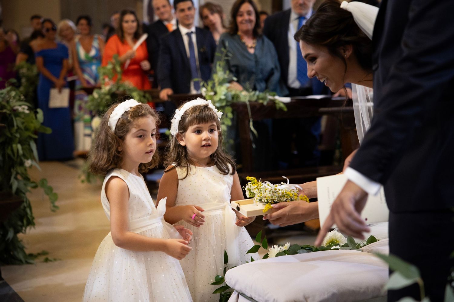 Young flower girls watch intently as wedding cake is being cut during reception.