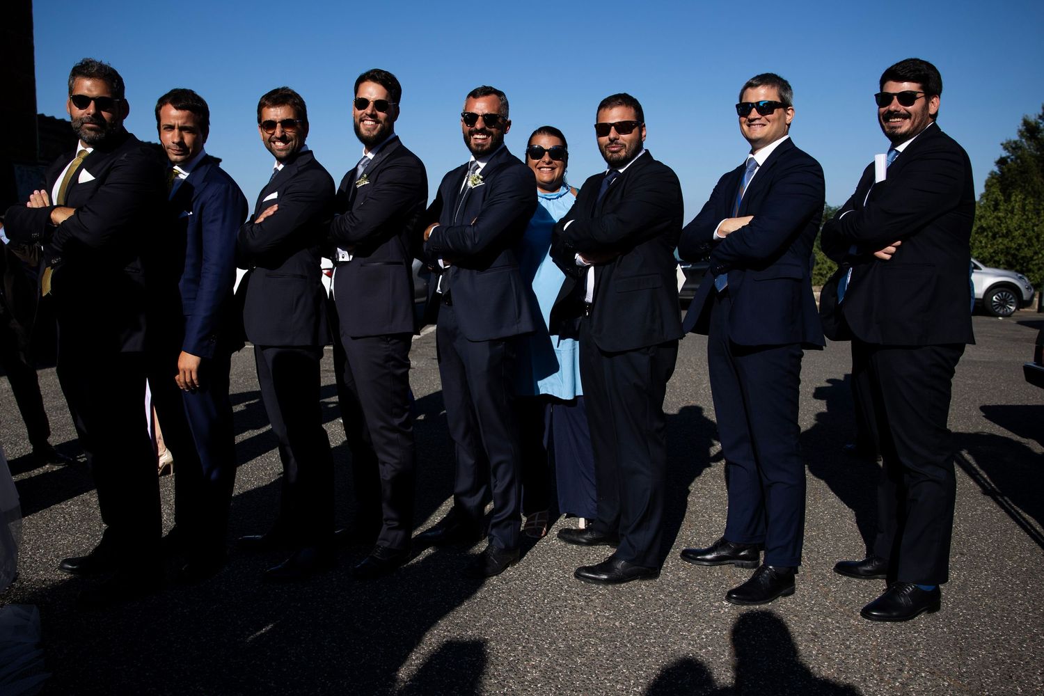 Groomsmen in matching dark suits and sunglasses pose in dramatic lighting.
