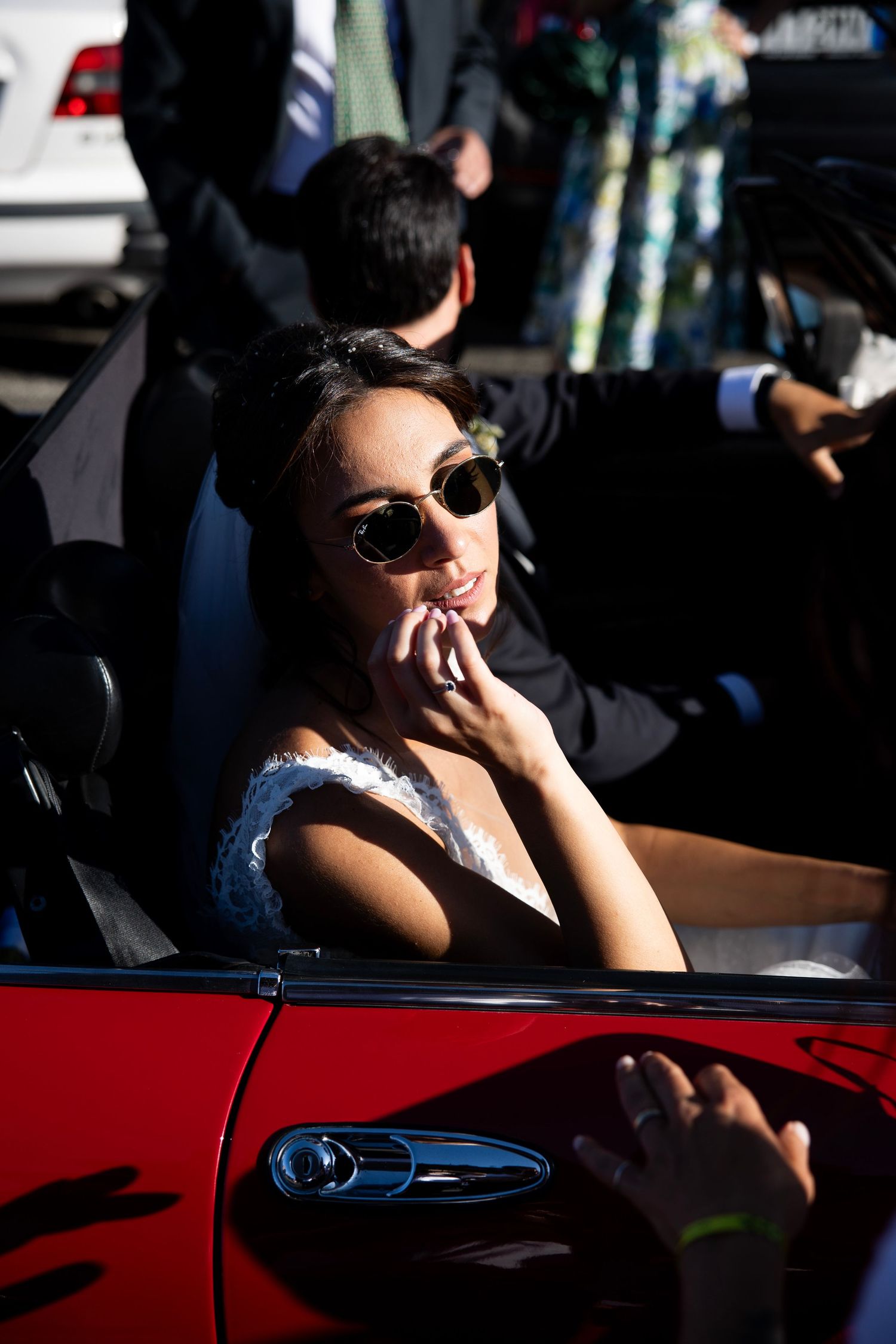 A person in sunglasses sits stylishly in a red convertible car.