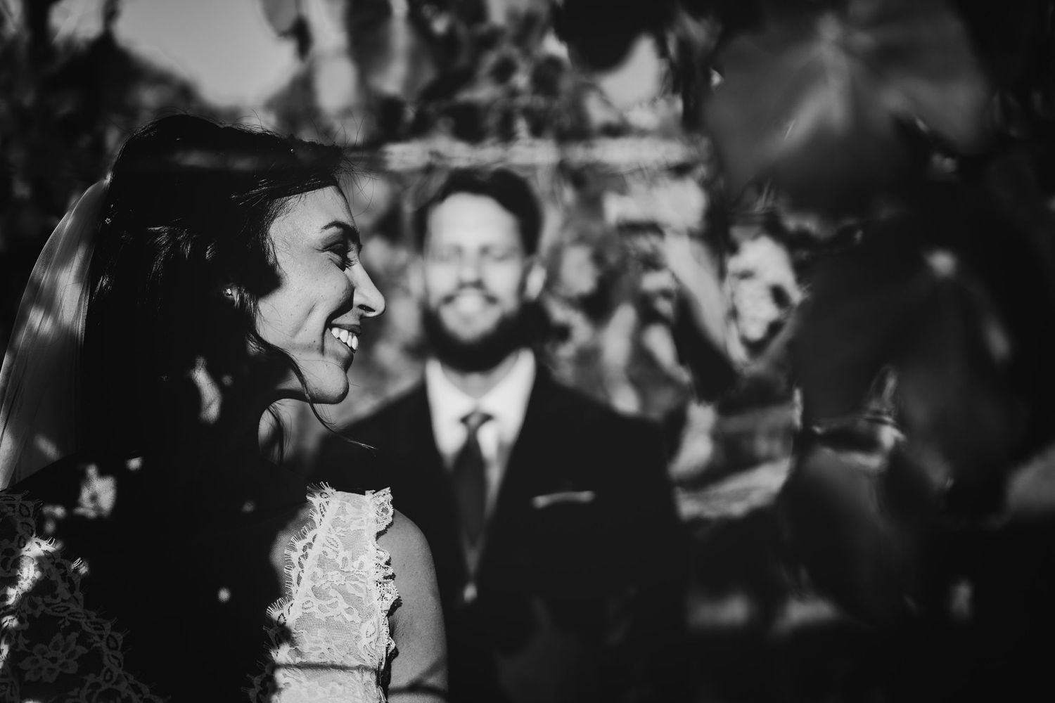 A black and white candid wedding photo capturing joyful laughter during celebrations.