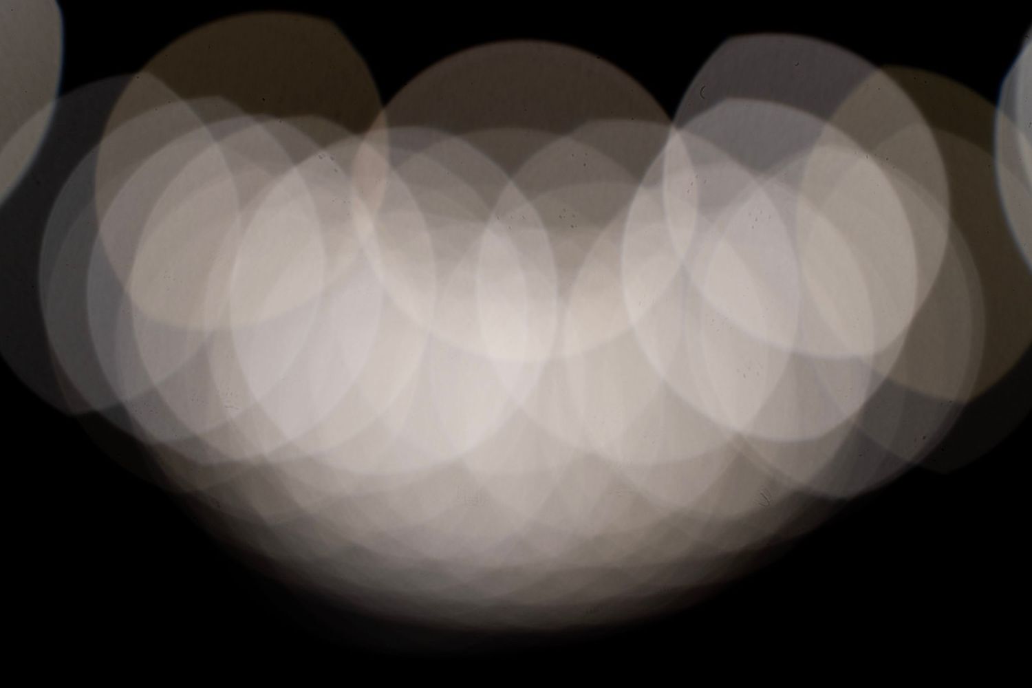 Abstract bokeh light pattern creating a curved shape against dark background.