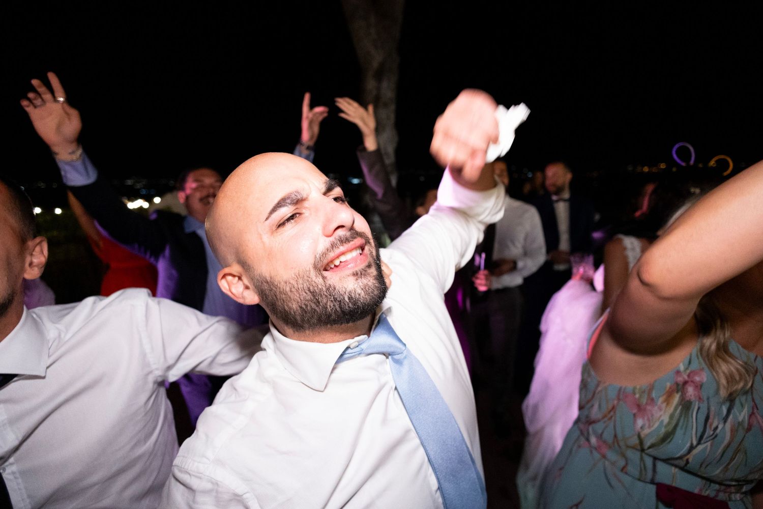 Energetic dancing and celebration at a nighttime wedding reception.