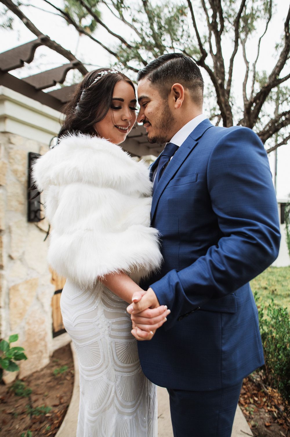 An intimate wedding portrait of a couple sharing a close moment, with the bride wearing a white fur stole.