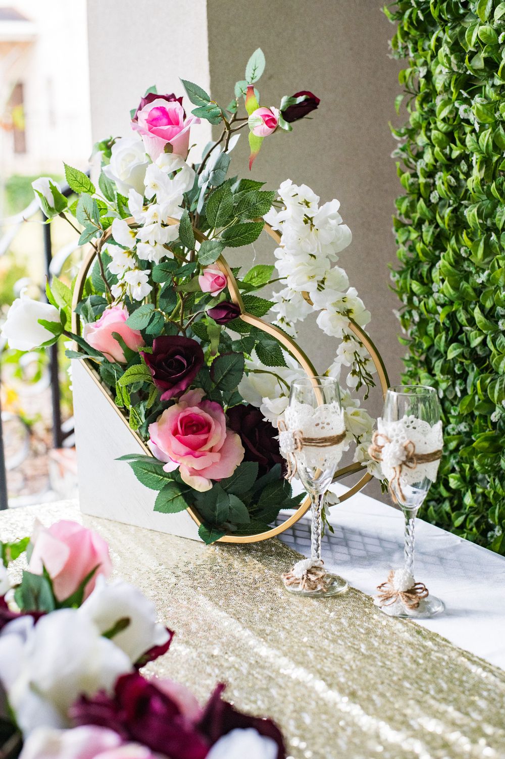 Wedding table decor featuring floral arrangements and champagne glasses on a gold sequined runner.