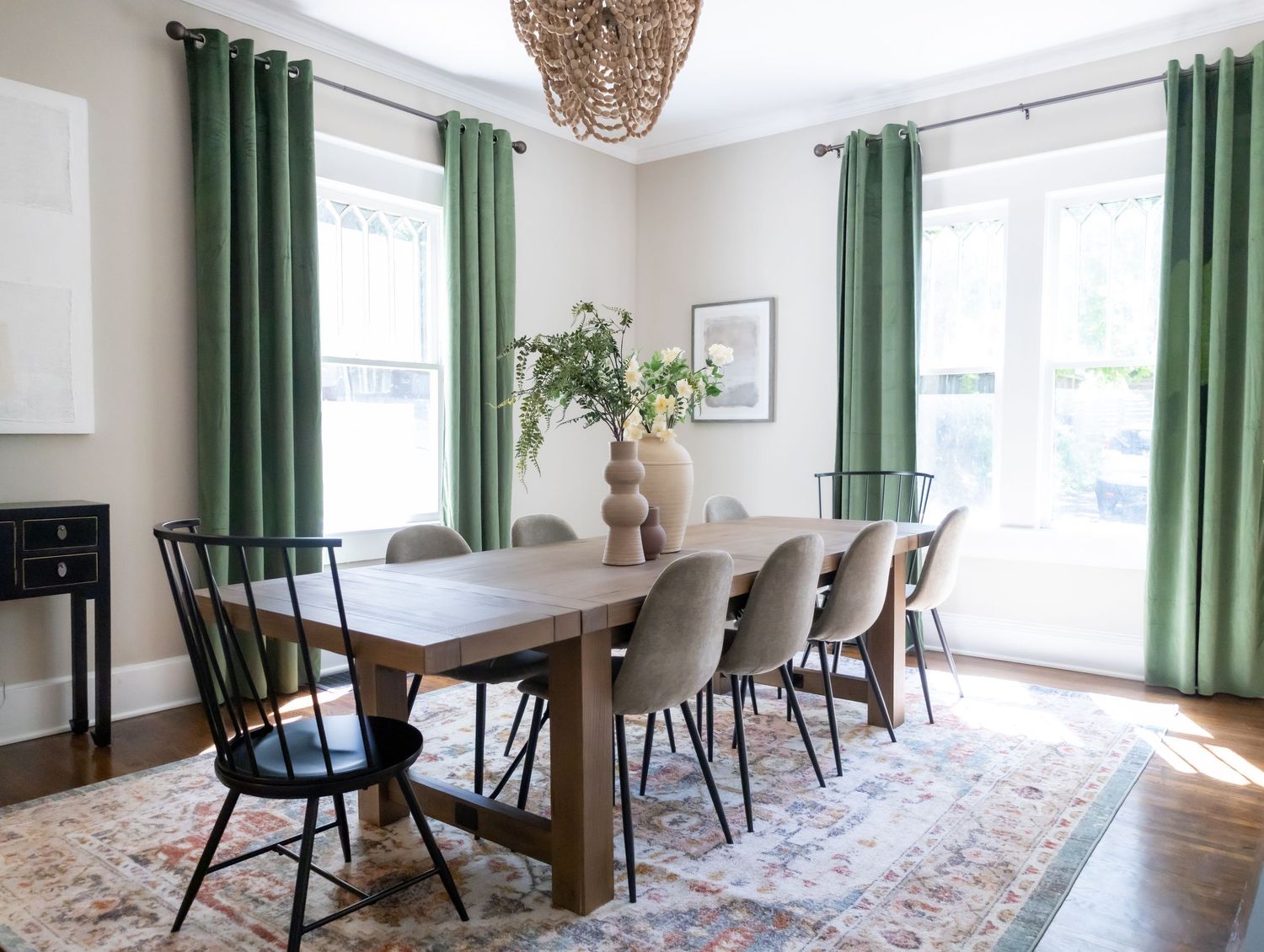 Stylish dining room table with green accents, wooden table, and plants.