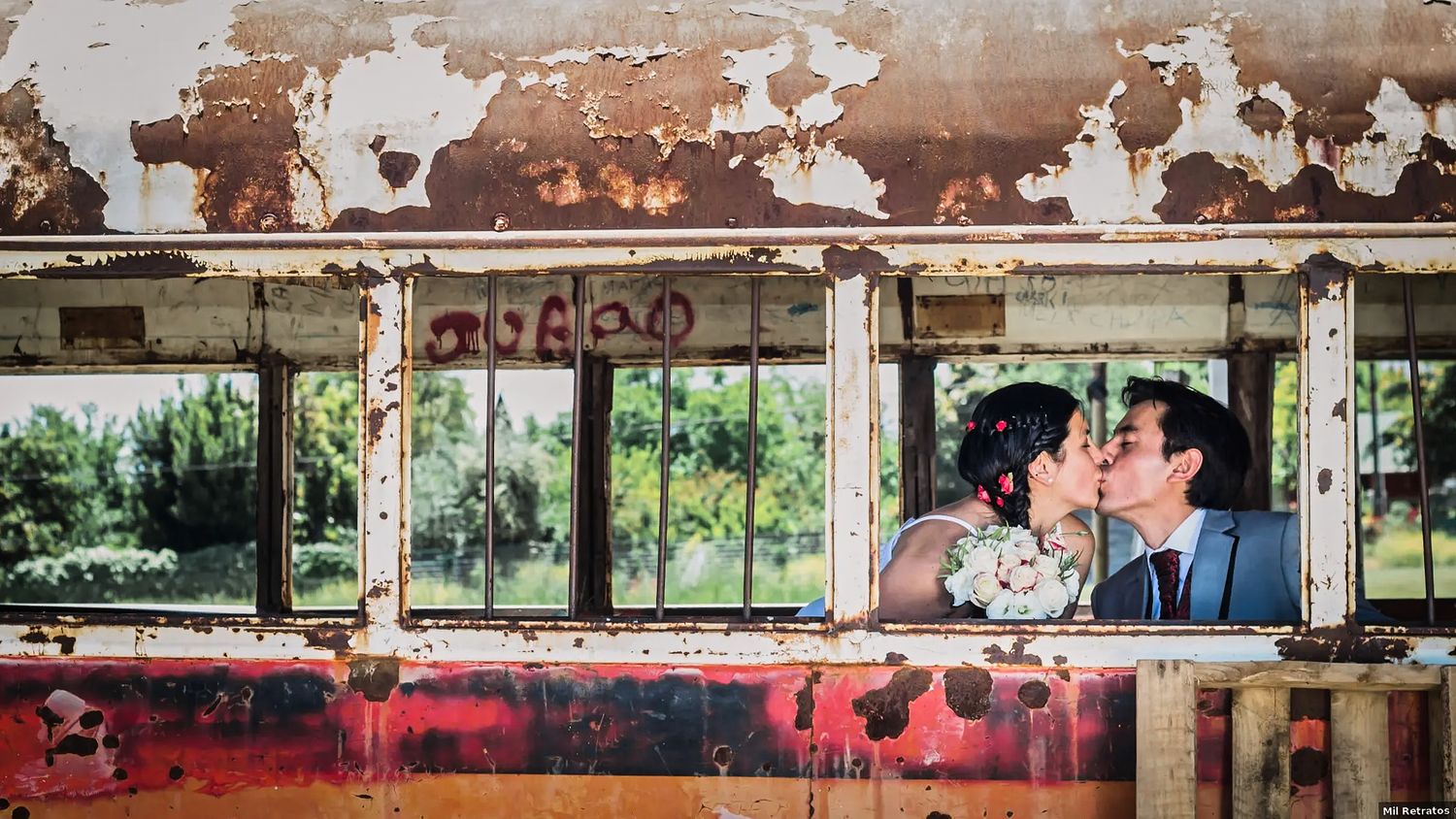 Couple sharing romantic kiss in rustic vintage train car setting.
