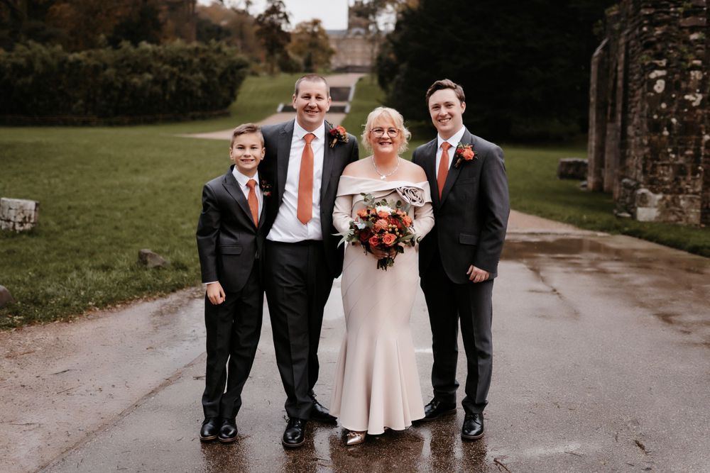 Small wedding party poses together on wet pathway outdoors at The Orangery Margam Park