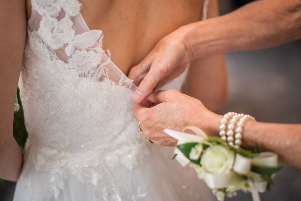 mother of the bride zipping up brides wedding dress before the ceremony