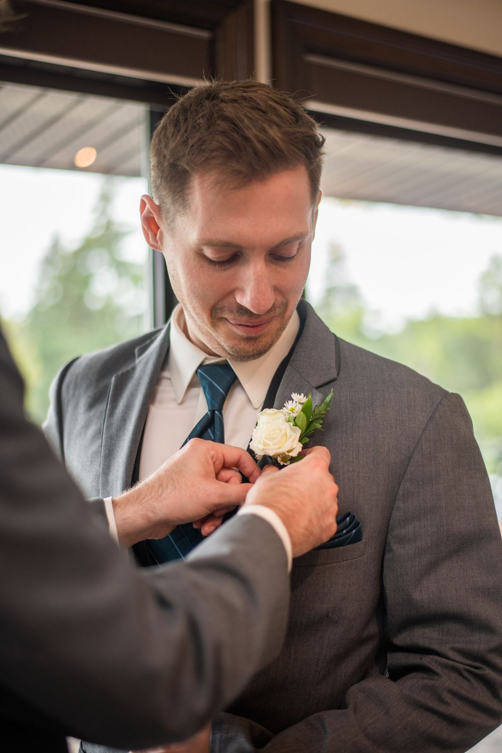 best man pinning boutonniere on groom before wedding ceremony at Stratford Country Club