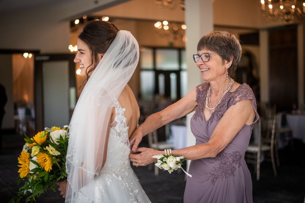 mother of the bride zipping up brides wedding dress before the ceremony