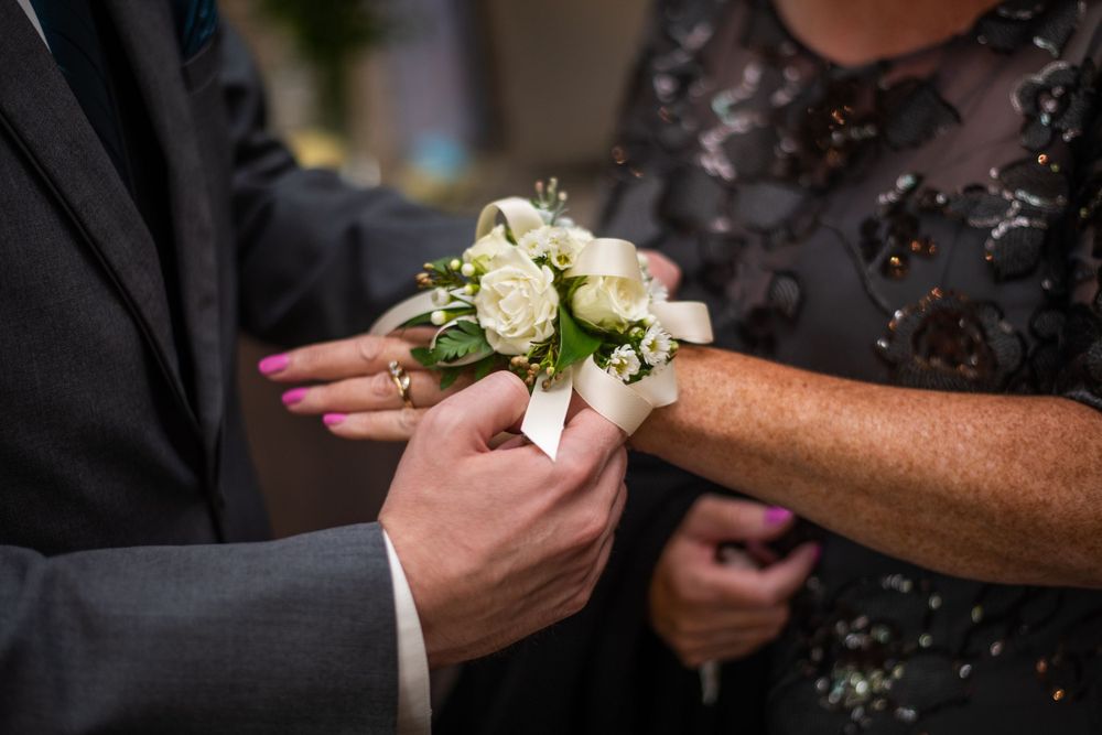 close up groom putting corsage on mother of the groom before wedding ceremony at Stratford Country Club