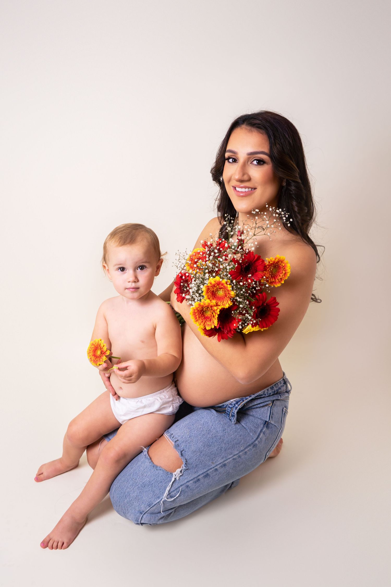 Pregnant mother and daughter smiling with red and yellow flowers at maternity photoshoot in Doncaster.