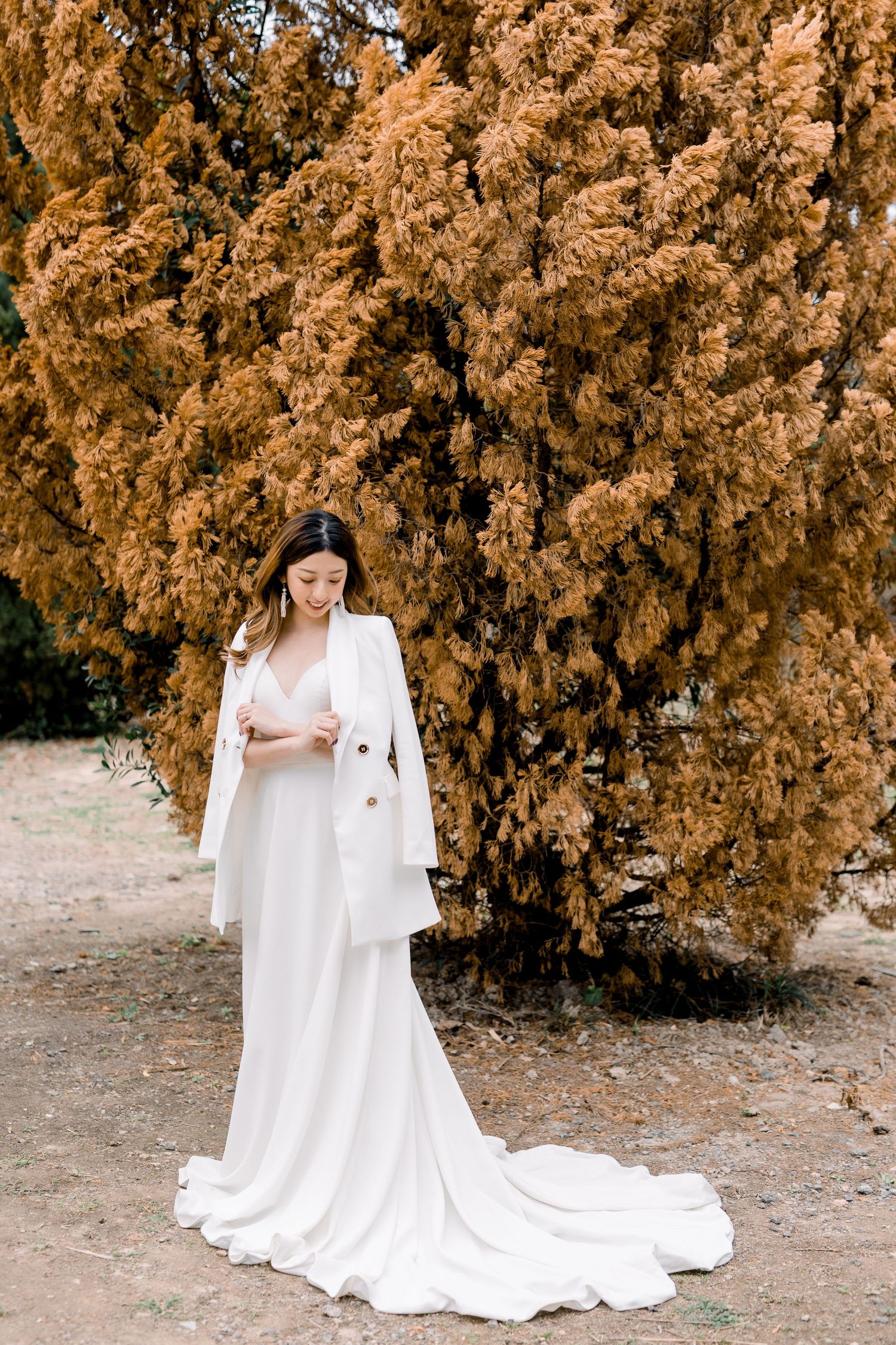 Beautiful flowing white wedding dress train contrasts against golden autumn leaves.