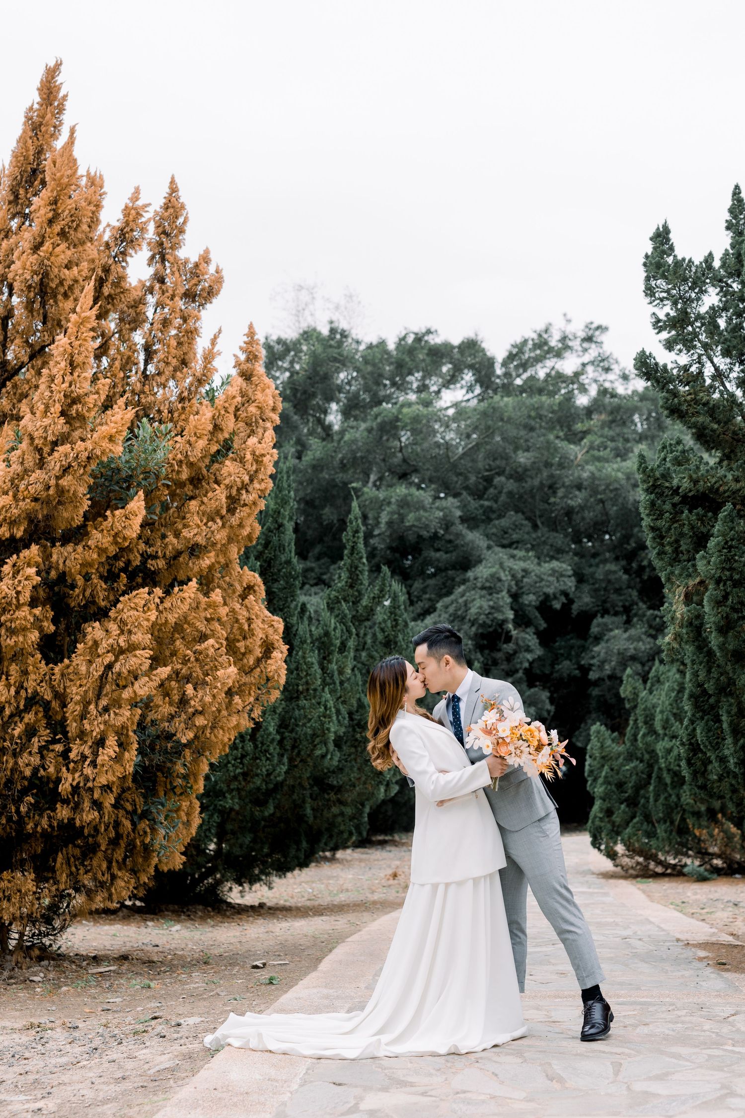 Romantic wedding photography session along a garden path with warm autumn colors.