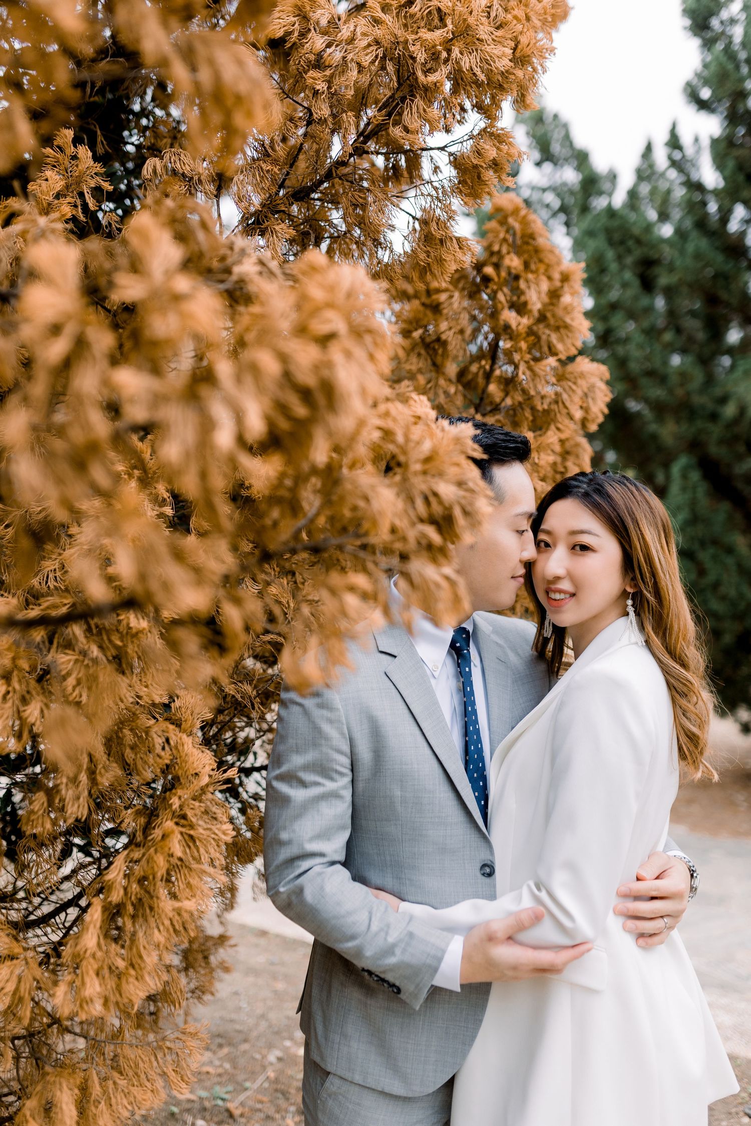 A romantic moment captured between a couple against autumn-colored foliage.