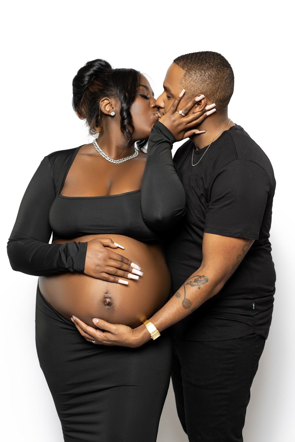 Intimate maternity portrait of couple in black outfits sharing tender moment.