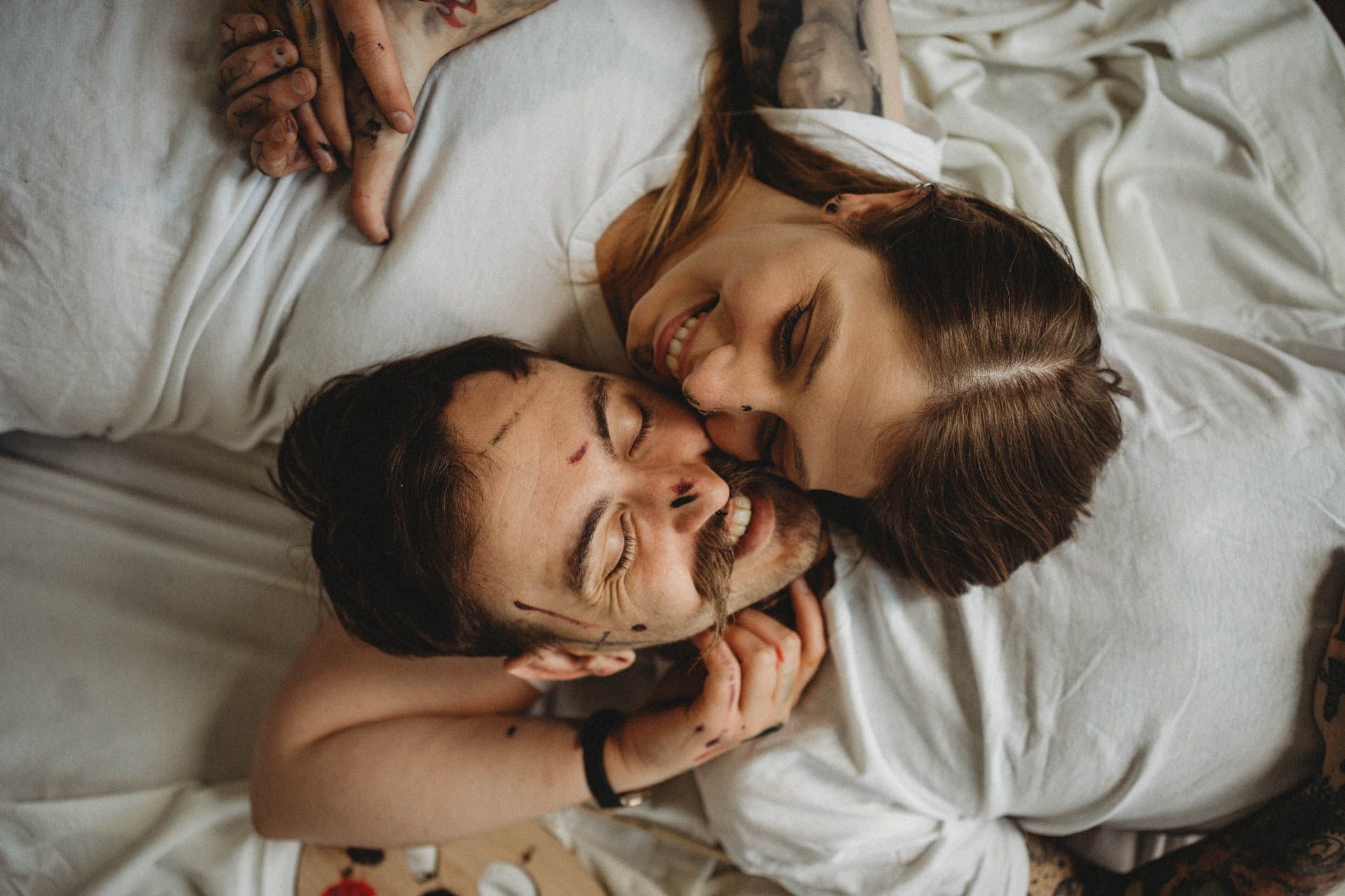 An intimate moment captured between two people on white bedding.