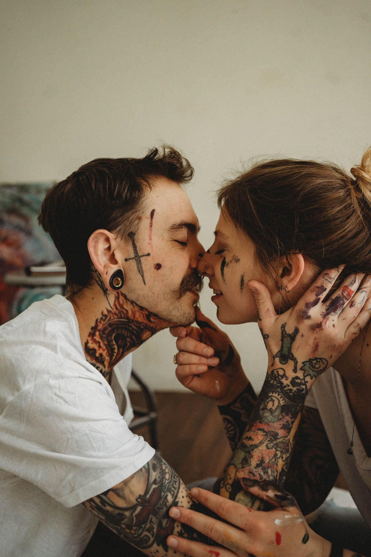 A close-up artistic portrait of a tattooed couple sharing an intimate moment.