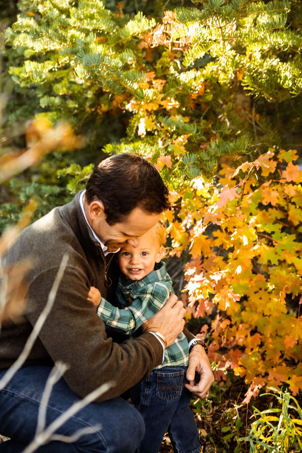 Tender moment between parent and child surrounded by golden autumn leaves.